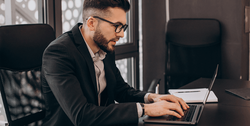 Gestor empresarial usando laptop em ambiente de escritório moderno, focado em soluções de gestão, impostos e consultoria com Dootax.