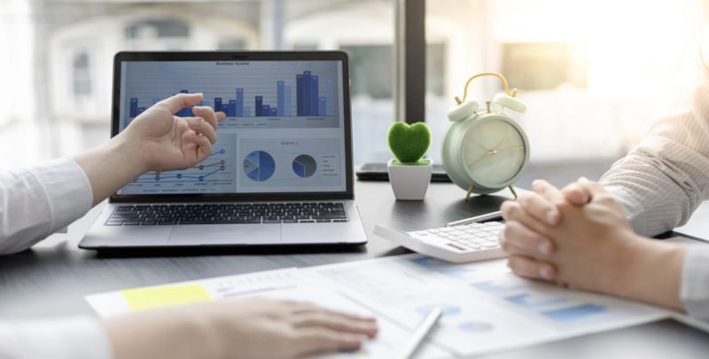 Relatório financeiro no notebook com gráficos e análises, ambiente de escritório.