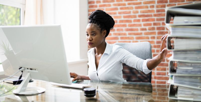 Dootax mulher organizando documentos e usando computador para gestão financeira e contábil, otimização de processos fiscais com plataforma digital confiável e segura.