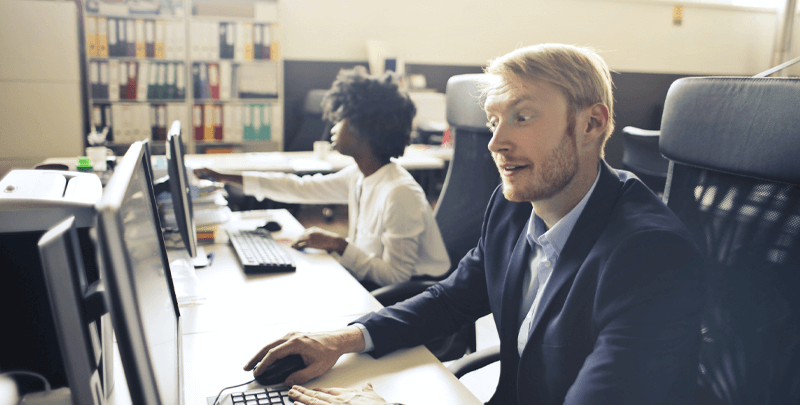 Tax professionals trabalhando em escritório com computadores para soluções fiscais eficientes.