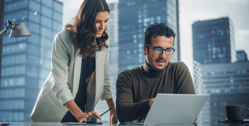 Gestores de negócios analisando dados financeiros com laptop em ambiente corporativo moderno | Dootax.