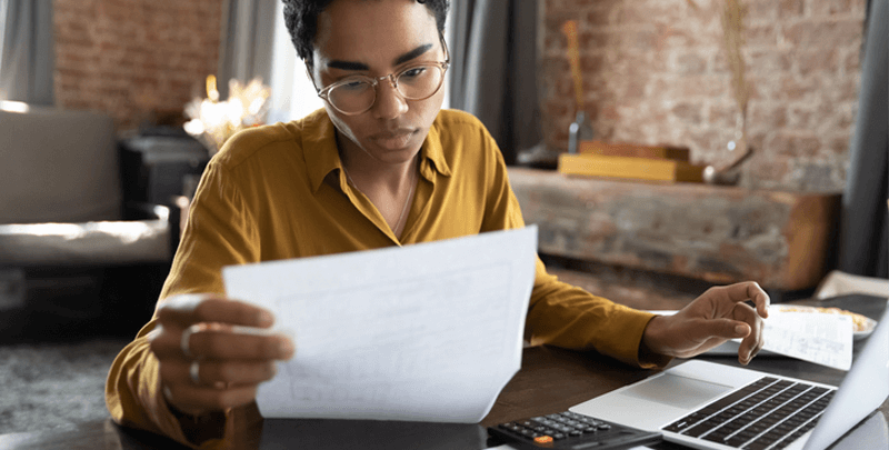 Executivo analisando documentos financeiros com computador e calculadora, promovendo otimização contábil e serviços de assessoria tributária na plataforma Dootax.