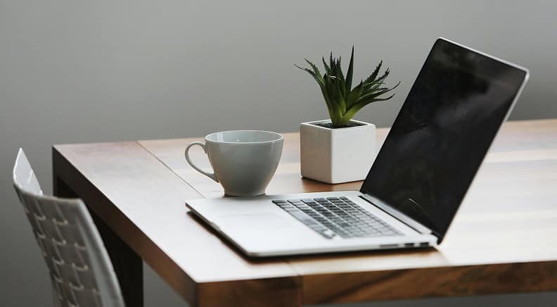 Computador em cima da mesa com xícara de café