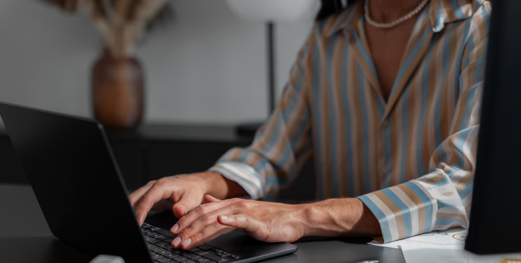 1. Mulher usando laptop em ambiente de trabalho, foco em empresa de tecnologia e soluções digitais para gestão de impostos e tributos.