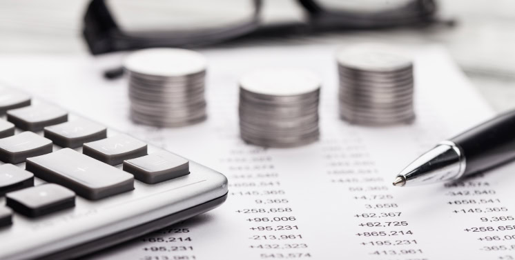 1. Calculadora financeira, pilhas de moedas e caneta sobre documento de análise de dados econômicos, foco em soluções fiscais e tributárias com Dootax.